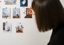 A woman choosing photos on a pinboard.